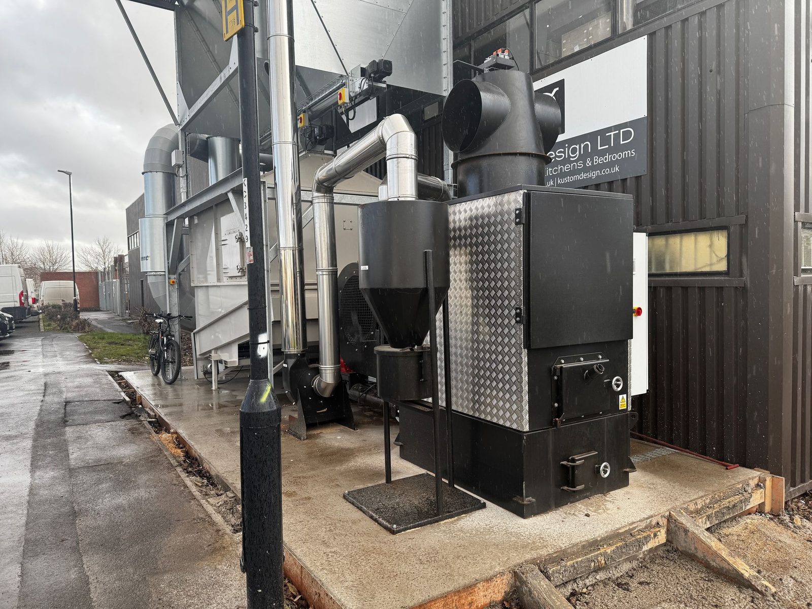 Rear view of an installed Ranheat WA 150 black warm air heater beside a galvanised B10 bunker silo with diamond-plate cladding